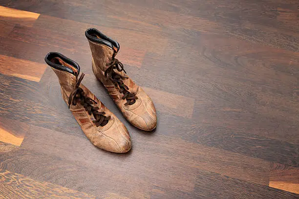 Pair of vintage leather baseball shoes on hardwoodfloor with copy space