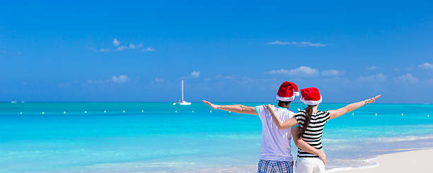 istock Young romantic couple in Santa hats during beach vacation 531110389