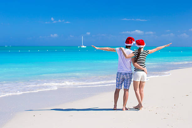 istock Young romantic couple in Santa hats during beach vacation 531110413