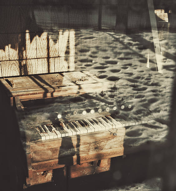 An antique pipe organ sits in the front porch of an abandoned home with a reflection of snow outside.