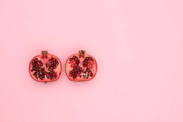 Fresh pomegranate cut in half on pastel pink stock photo