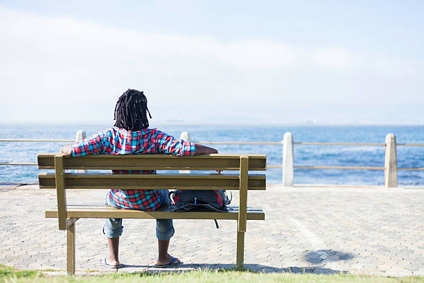 istock African man sitting on a bench by the the ocean 531123929