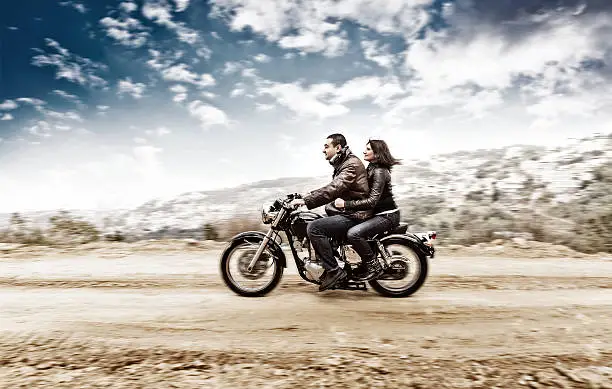 Active couple riding on the motobike, slow motion, having fun in bikers tour, vintage style photo, happy adventure concept