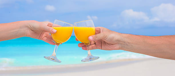 istock Two hands hold glasses with orange juice background blue sky 531135223