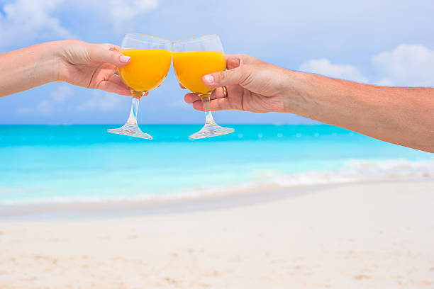 istock Two hands hold glasses with orange juice background blue sky 531135249