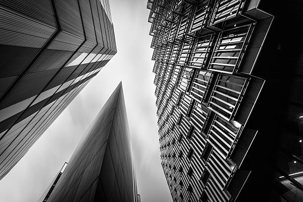 Abstract modern Business buildings in London's Financial District BW Highly detailed abstract wide angle view up towards the sky in the financial district of London City and it's ultra modern contemporary buildings. Stot on Canon EOS 6D, wide angle of 17mm, ISO 100, f/10, long exposure of 30 seconds to blurr the clouds into the sky. Monochrome edit in Black and White image with high contrast. architecture capital cities glass pattern stock pictures, royalty-free photos & images