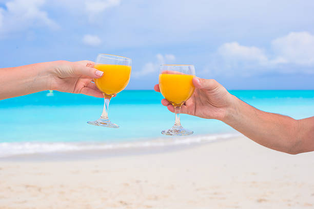 istock Two hands hold glasses with orange juice background blue sky 531137247