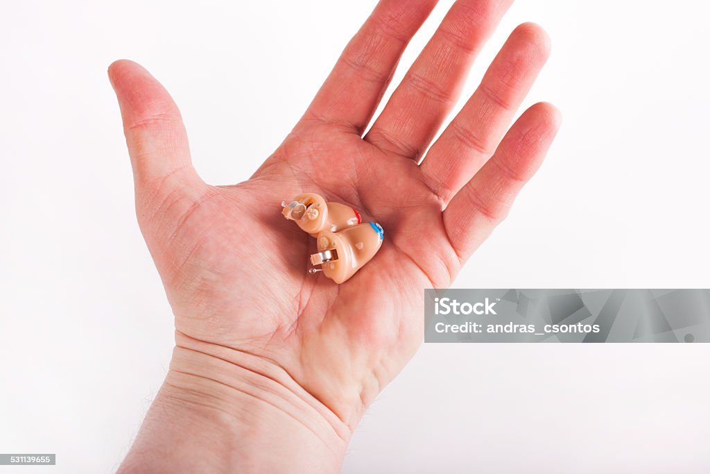 CiC hearing aids on a palm CIC (completely in the canal) left and right Hearing aids on a man's palm. Adult Stock Photo