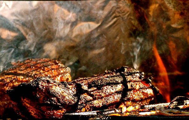 Steaks grilling on barbeque with flames and smoke