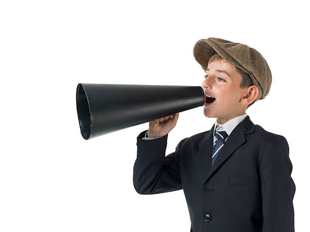 istock Little boy with newsboy cap shouting on old fashioned megaphone 531147691