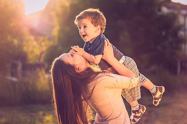 Mother lifting her son up stock photo
