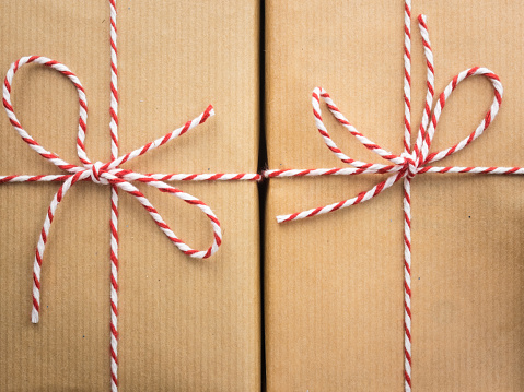 detail of  two string and brown paper parcels : red and white striped  string bows against brown wrapping paper