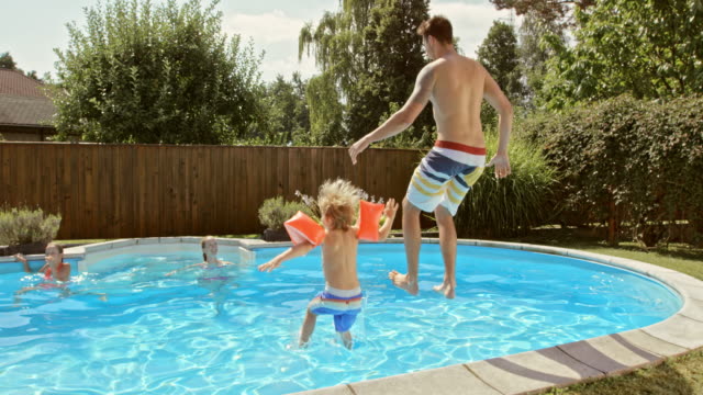SLO MO CS Father and son jumping into the pool together