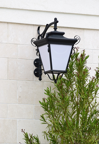 New street lamp in the classical style, on the stone wall, with oleander in front