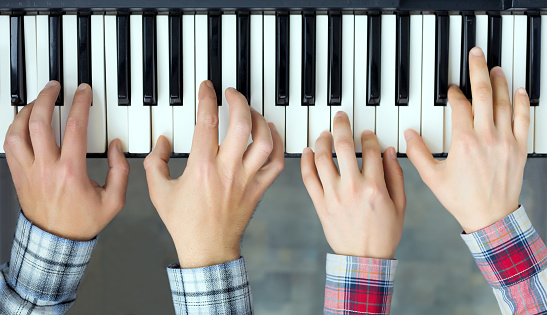 Piano Keyboard top View Hands of Man and Woman playing