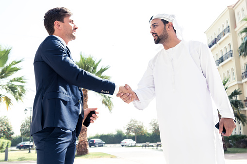 An Arab office executive and an european business shaking hands over a business agreement.