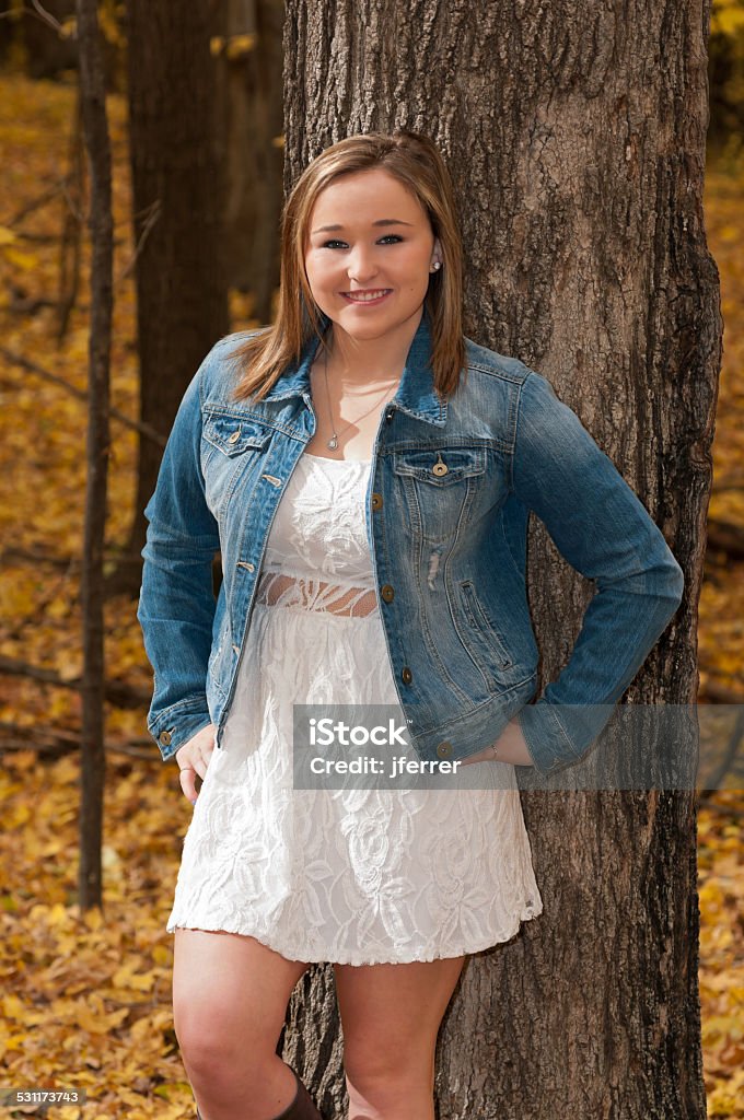 Young Female Model Against Forest Tree three quarter length portrait of young female teen smiling and standing against tree in autumn forest Females Stock Photo