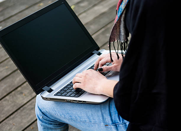 Side view of woman's hands writing on laptop. stock photo