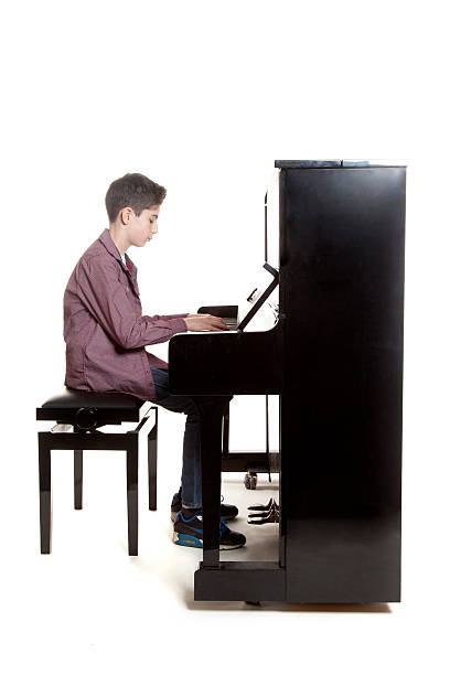istock teenage boy sits at upright piano in studio 531175603