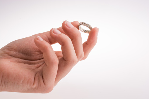 Hand holding a ring on a white background