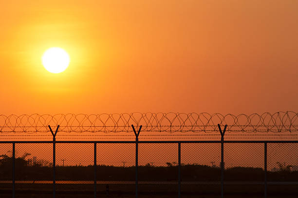 Silhouette security with a barbed wire fence at sunset time