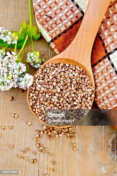 Buckwheat In Spoon On Board With Flower And Doily Stock Photo - Download Image Now - 2015, Breakfast, Brown