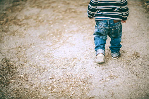 closeup photo of little boy's legs walking on the road