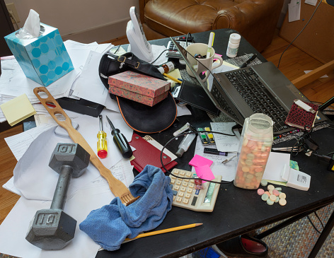 Messy desktop with laptop, antacid tablets, back scratcher, and dumbbell. Canon EOS 5Ds, 24 mm.