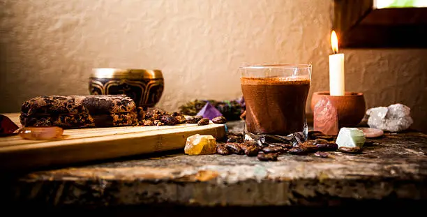 Ceremonial Cacao Beverage (Raw Chocolate), surrounded by ingredients, gemstones, a Tibetan singing bowl and candle.
