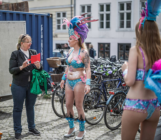 Young women parading in the Copenhagen Whitsun Carnival, 2016. Copenhagen, Denmark - May 14, 2016: Young women ready to enter the parade in the Copenhagen Whitsun Carnival, 2016 talking to a bystander. whitsun stock pictures, royalty-free photos & images