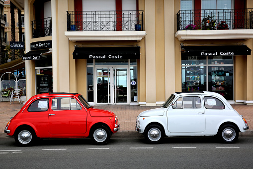 Menton, France - May 14, 2016: Two small Italian cars Fiat 500 Parked in a Parking Lot in Menton. The red car is a Fiat 500 R and the white is a Fiat 500 F