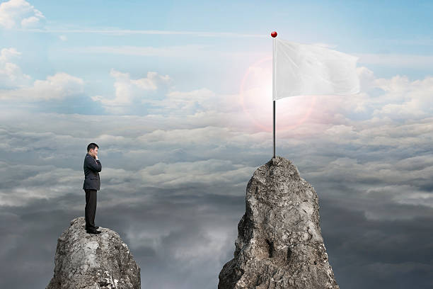 istock Businessman standing on peak with blank flag and sunlight clouds 531189709