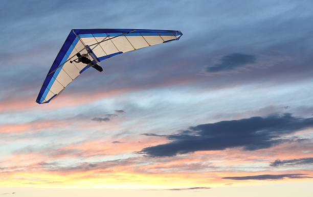 Hanglider Hanglider Flying over the ocean at sunset hang glider stock pictures, royalty-free photos & images
