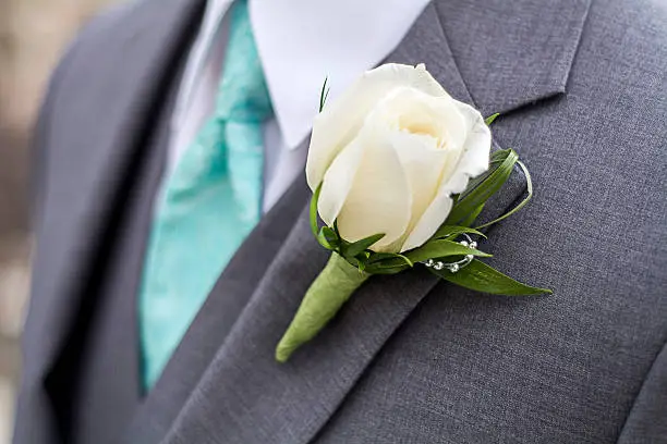 grey suit with blue tie and large white rose boutonniere 