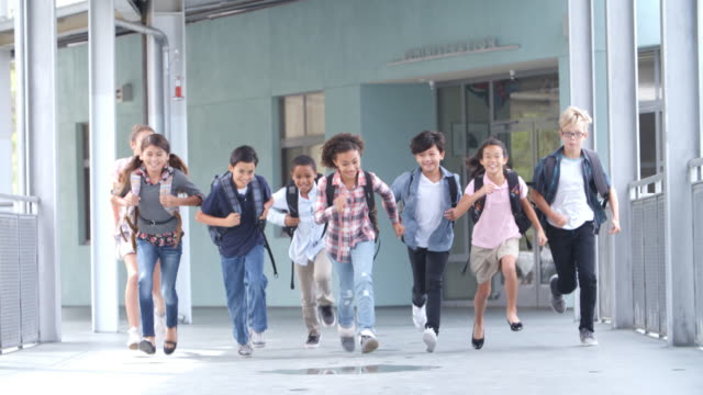 Group of 5th grade school kids running in a school corridor