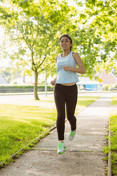 istock Fit young woman jogging through the park 531214149