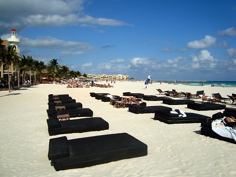 Playa Del Carmen, Mexico - January 27, 2010: Central beach in Playa Del Carmen. Locals and tourists enjoying walking and sunbathing on cozy lounge sun beds on the beautiful white sand beach, looking the Caribbean sea.