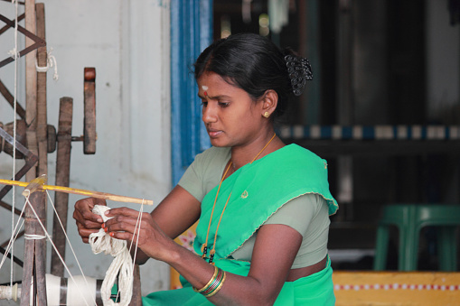 Ponduru, Andhra Pradesh, India - December 16, 2014: Unknown lady making the cotton loom roll using traditional charaka which was used by great freedom fighter, Mahatma Gandhi.