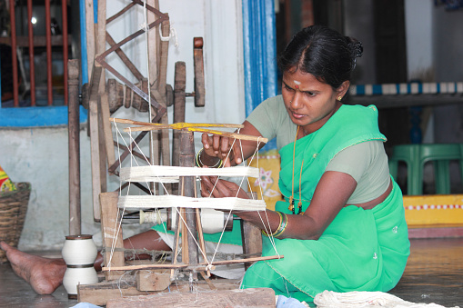 Ponduru, Andhra Pradesh, India - December 16, 2014: Unknown lady making the cotton loom roll using traditional charaka which was used by great freedom fighter, Mahatma Gandhi.