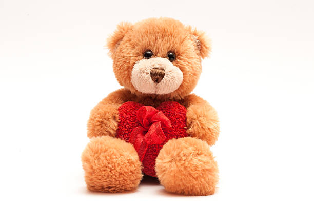 istock Isolated teddy bear holding a heart with a ribbon. 531227821