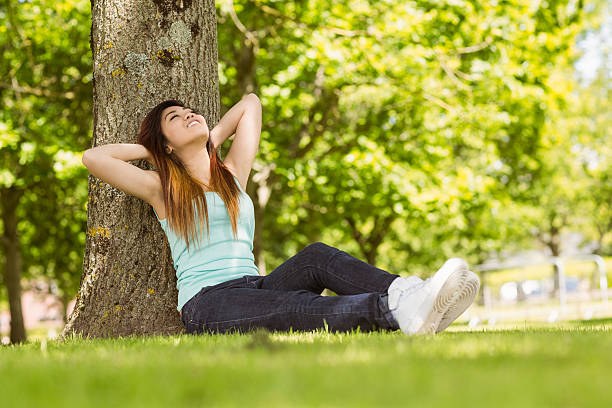 istock Beautiful woman sitting against tree in park 531230751