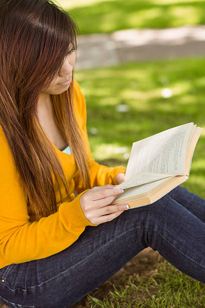 istock Relaxed female student reading book in park 531230781