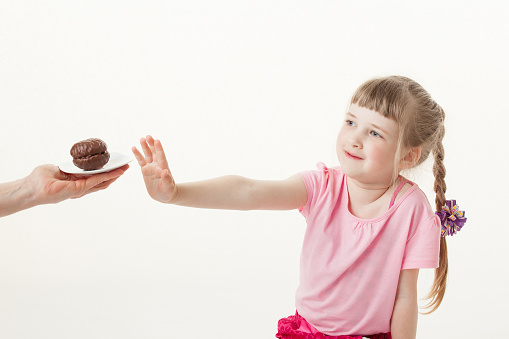 Pretty little girl regecting a chocolate cake, white background