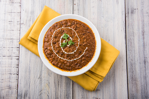dal makhani or dal makhani or daal makhni or kali dal with fresh cream and Coriander topping, served in a bowl, isolated