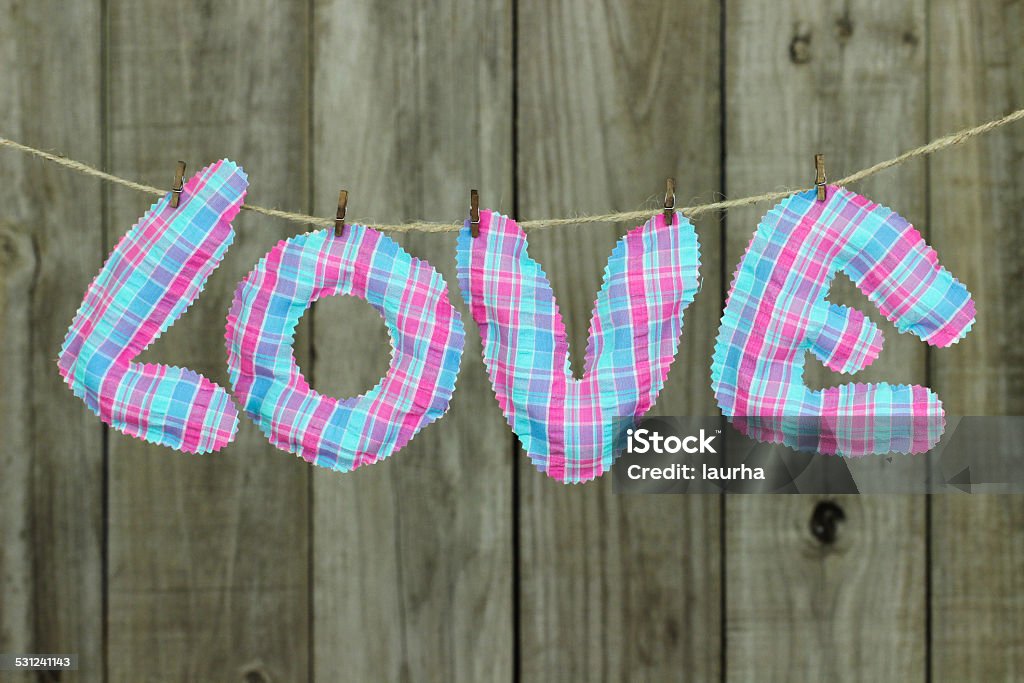 Pink and blue LOVE text hanging on clothesline Pink and teal blue LOVE text hanging on clothesline by rustic wood background 2015 Stock Photo