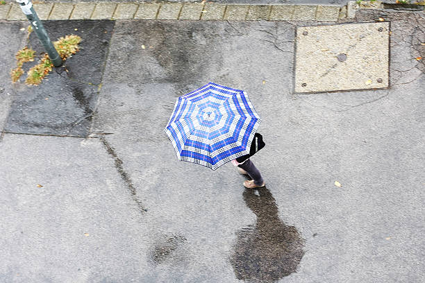 hombre caminando bajo una sombrilla - checking for rain fotografías e imágenes de stock