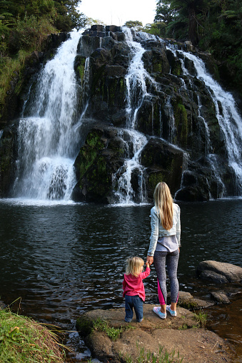 Mother and baby standing near the waterfall, New Zealand