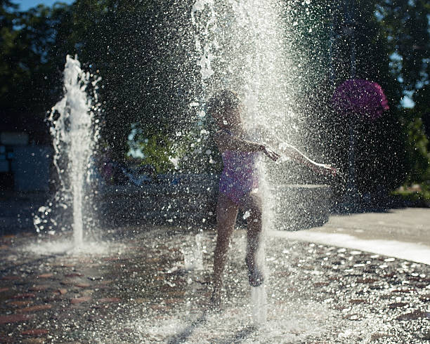 istock Young girl playing in a fountain . 531243774