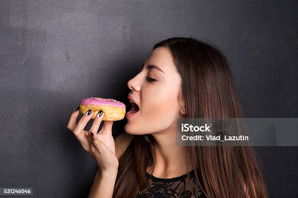 Girl Eating A Donut Stock Photo - Download Image Now - Doughnut, Eating, Women