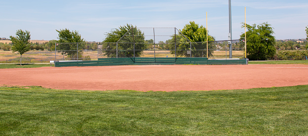 Little league baseball field with green grass, brown dirt and no people